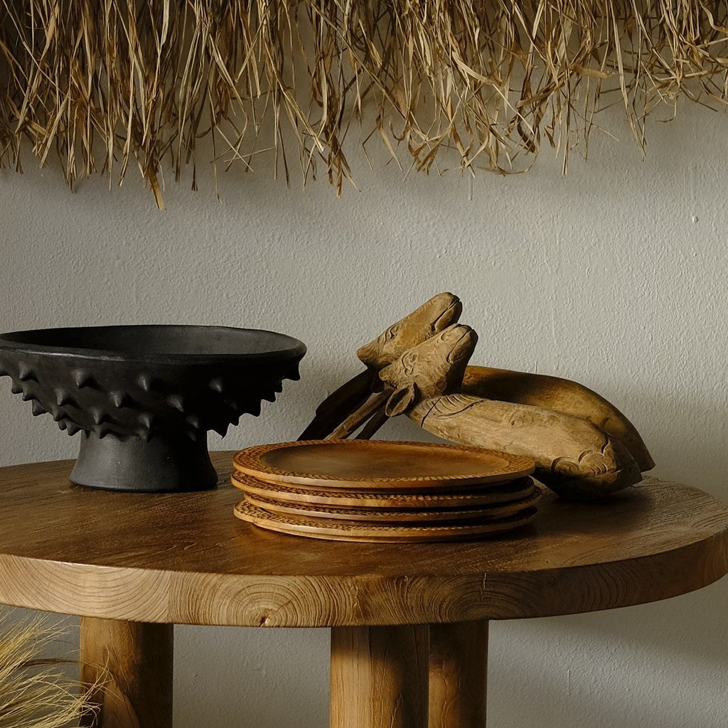 Tablescape with hand knotted wall hanging, teak plates, and deer head sculptures 