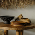 Tablescape with hand knotted wall hanging, teak plates, and deer head sculptures 