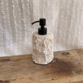 Onyx soap dispenser with steel pump on vintage wooden surface with white textile background - wabi sabi bathroom